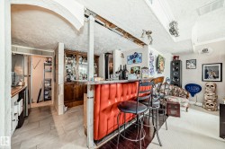 Custom wet bar featuring upholstered red paneling and three bar stools - 