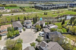 Aerial perspective featuring a residential cul-de-sac with various home styles, verdant landscaping, and proximate natural water features - 