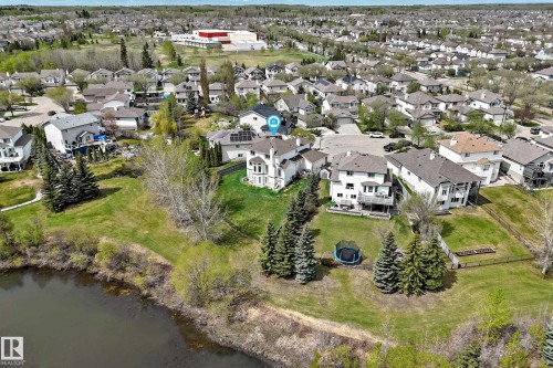 Expansive property featuring a waterfront setting, mature evergreen trees, and a spacious green lawn - 5107 200 Street, Edmonton, AB - Outdoor With Body Of Water With View