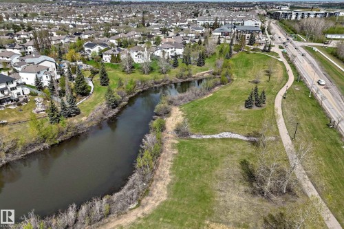 Expansive green space featuring a winding river, mature evergreen trees, and a paved walking path - 5107 200 Street, Edmonton, AB - Outdoor With Body Of Water With View