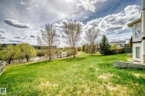Expansive grassy yard with mature trees and a tranquil pond border - 5107 200 Street, Edmonton, AB - Outdoor