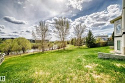 Expansive grassy yard with mature trees and a tranquil pond border - 