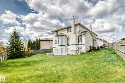 Expansive green lawn surrounds the property, featuring a beige exterior with dark trim accents - 5107 200 Street, Edmonton, AB - Outdoor