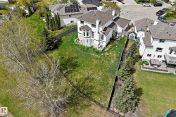 Expansive rear yard featuring green lawn, mature trees, and a black chain link fence - 