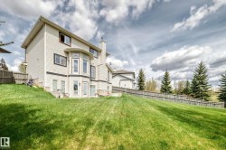 Rear exterior featuring light-colored siding with dark trim, a bay window on the main level, and multiple glass-paned doors providing direct yard access - 