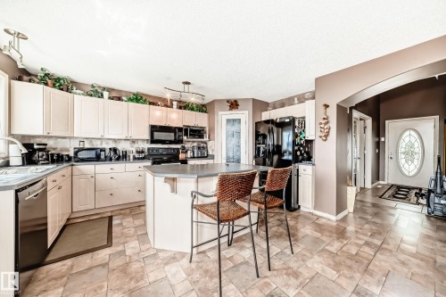 Kitchen featuring an island with seating, extensive cream cabinetry. - 5107 200 Street, Edmonton, AB - Indoor Photo Showing Kitchen