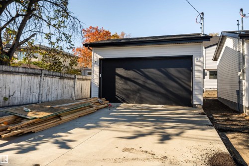 Detached garage featuring horizontal siding, a black overhead door, black gutters, and a concrete driveway - 12031 124 Street Nw, Edmonton, AB - Outdoor