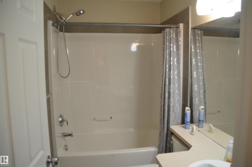Bathtub and shower combination with a curved shower curtain rod, chrome fixtures, and a white acrylic surround - 1412 152, Edmonton, AB - Indoor Photo Showing Bathroom