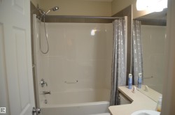 Bathtub and shower combination with a curved shower curtain rod, chrome fixtures, and a white acrylic surround - 