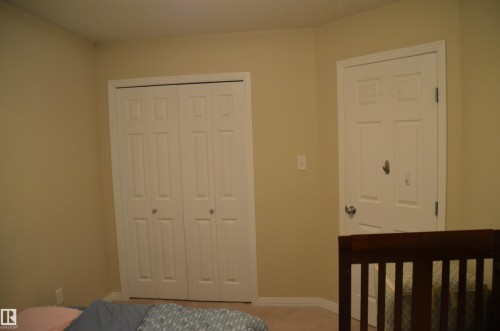 Neutral-toned walls and carpet flooring define this interior space, featuring a white bi-fold closet and a matching paneled door - 1412 152, Edmonton, AB - Indoor Photo Showing Bedroom