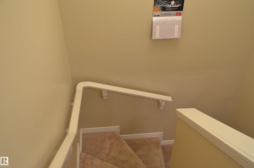 Carpeted staircase with white handrails and painted beige walls - 1412 152, Edmonton, AB - Indoor