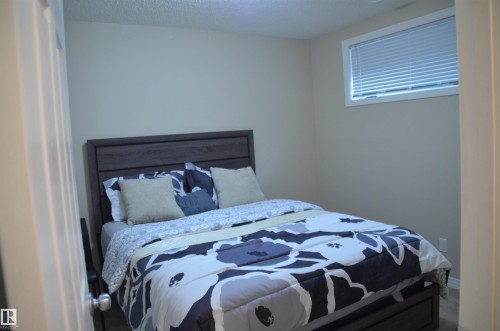 Bedroom featuring neutral wall color, window with blinds, and dark wood-finish bed frame - 1412 152, Edmonton, AB - Indoor Photo Showing Bedroom
