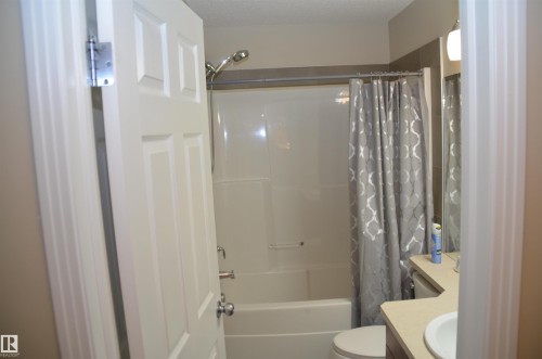 Bathroom featuring a white shower-over-tub unit, a toilet, and a vanity with an integrated sink - 1412 152, Edmonton, AB 