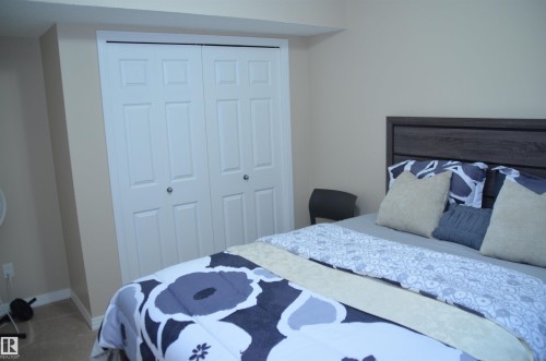 Bedroom featuring neutral wall paint, white trim, and bi-fold closet doors with round chrome hardware - 1412 152, Edmonton, AB 