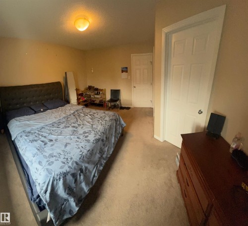 Carpeted room featuring a white paneled door, light-colored walls, and a ceiling-mounted light fixture - 1412 152, Edmonton, AB 