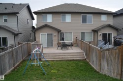 Rear exterior featuring a spacious wooden deck with steps to a grassy yard - 
