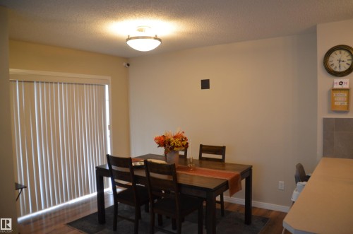 Dining area featuring wood-finish flooring, a contemporary flush-mount ceiling light, and direct access to outdoor space via a glass door with vertical blinds - 1412 152, Edmonton, AB - Indoor Photo Showing Dining Room