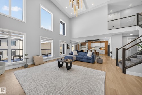 Expansive living space featuring high ceilings, large windows, light wood flooring, and a modern chandelier - 6614 39 Avenue, Beaumont, AB - Indoor