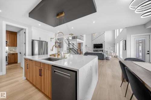 Spacious kitchen with a large island featuring a sink, stainless steel dishwasher, and light wood cabinetry - 6614 39 Avenue, Beaumont, AB - Indoor Photo Showing Kitchen With Double Sink