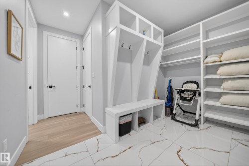 The property features built-in white shelving, a built-in white bench with coat hooks, and white tile flooring with brown veining - 6614 39 Avenue, Beaumont, AB - Indoor