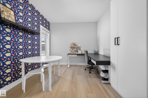 Versatile room featuring light-toned flooring, a window providing natural light, and a built-in white wardrobe with black handles - 6614 39 Avenue, Beaumont, AB - Indoor Photo Showing Office