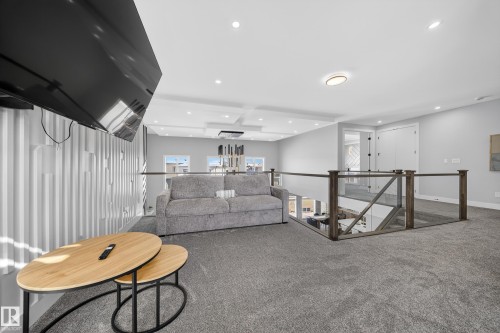 Spacious upper level featuring gray carpeting, recessed lighting, and a glass and wood railing overlooking the level below - 6614 39 Avenue, Beaumont, AB - Indoor Photo Showing Other Room