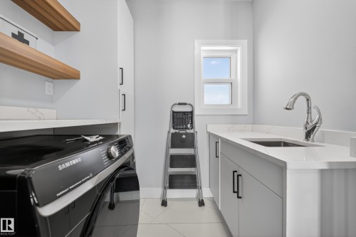 The utility room features light-colored walls, a window providing natural light, and a countertop with an integrated sink and chrome faucet - 6614 39 Avenue, Beaumont, AB - Indoor Photo Showing Other Room
