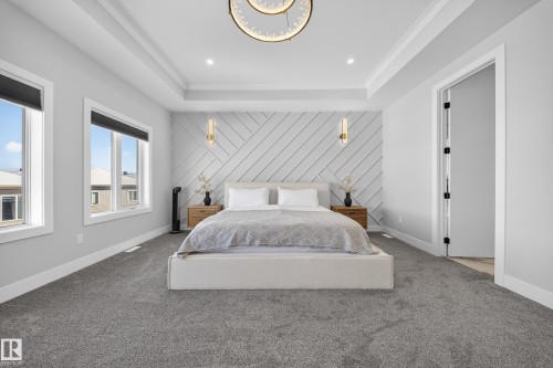 This property features a spacious bedroom with light gray walls, plush gray carpeting, and a tray ceiling - 6614 39 Avenue, Beaumont, AB - Indoor Photo Showing Bedroom