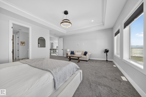 Spacious room featuring light gray walls, gray carpet, and a tray ceiling with a modern light fixture - 6614 39 Avenue, Beaumont, AB - Indoor Photo Showing Bedroom