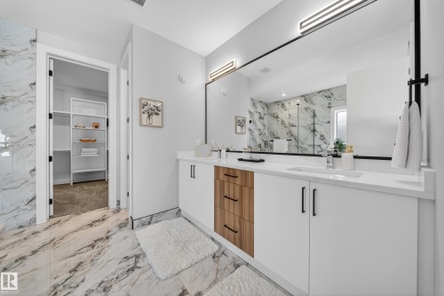 This bathroom features a double vanity with white countertops and cabinetry, complemented by wood-look drawers - 6614 39 Avenue, Beaumont, AB - Indoor