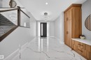 The property features a spacious entryway with marbled floors, a modern chandelier, and a built-in wooden storage unit with a white countertop - 6614 39 Avenue, Beaumont, AB  - Indoor Photo Showing Other Room 