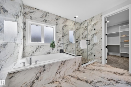Well-appointed bathroom featuring a built-in bathtub, a walk-in shower with a glass enclosure, and extensive marble-style tiling on the floors and walls - 6614 39 Avenue, Beaumont, AB - Indoor Photo Showing Bathroom