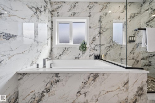 Bathroom featuring a built-in bathtub with polished chrome fixtures, white window, and marble-look wall and floor tiles - 6614 39 Avenue, Beaumont, AB - Indoor Photo Showing Bathroom