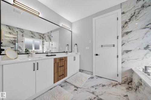The bathroom features a dual vanity with white cabinetry and wood-accented drawers, a large mirror, and tiled walls and flooring - 6614 39 Avenue, Beaumont, AB - Indoor Photo Showing Bathroom
