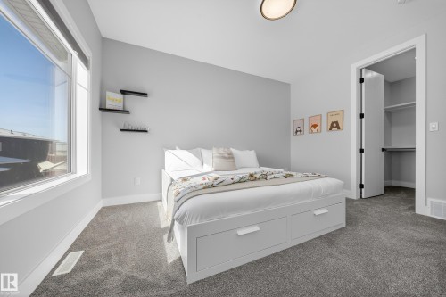 This room features neutral-toned walls, a large window, a built-in bed frame with storage drawers, and carpeted flooring - 6614 39 Avenue, Beaumont, AB - Indoor Photo Showing Bedroom