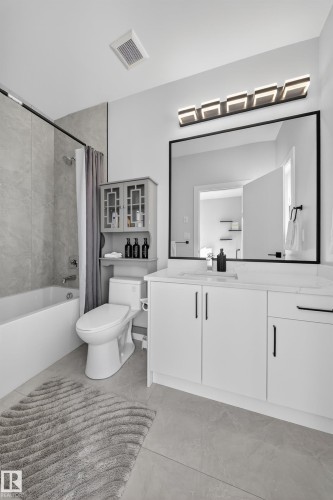 Bathroom featuring a vanity with white cabinetry, a large mirror, and a contemporary light fixture - 6614 39 Avenue, Beaumont, AB - Indoor Photo Showing Bathroom