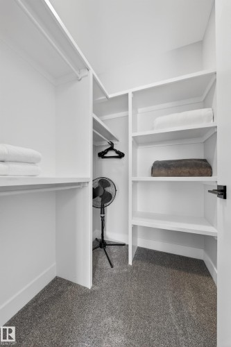 This closet features white shelving, white hanging rails, and grey carpeting - 6614 39 Avenue, Beaumont, AB - Indoor With Storage