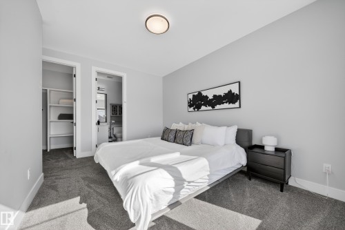 This bedroom features light gray walls, dark gray carpeting, and a modern ceiling light fixture - 6614 39 Avenue, Beaumont, AB - Indoor Photo Showing Bedroom