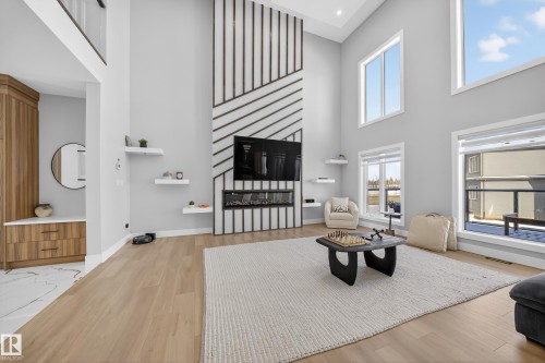 Spacious living area featuring high ceilings, light wood flooring, large windows, and a built-in fireplace with a media center - 6614 39 Avenue, Beaumont, AB - Indoor