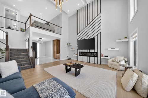 This expansive living area features high ceilings, light wood flooring, and a contemporary fireplace integrated into a striking accent wall - 6614 39 Avenue, Beaumont, AB - Indoor Photo Showing Living Room