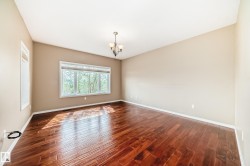 Spacious room featuring rich wood-finish flooring, a large multi-pane window, and a complementary single-pane window - 