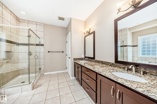 Bathroom featuring a dual vanity with granite countertops, undermount sinks, and a mosaic tile backsplash - 527 Callaghan Point(E), Edmonton, AB - Indoor Photo Showing Bathroom