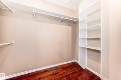 Custom closet system featuring wood-finish flooring, white baseboards, and built-in shelving units - 