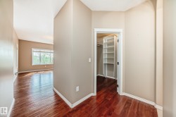 Hallway featuring rich wood-finish flooring, light tan wall paint, and white trim - 