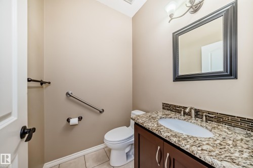 Powder room featuring a dark wood vanity with a granite countertop, undermount sink, and brushed nickel faucet - 527 Callaghan Point(E), Edmonton, AB - Indoor Photo Showing Bathroom