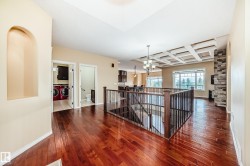 Rich wood-finish flooring throughout, coffered ceiling detail, contemporary chandelier, stone accent wall, and built-in wall niche - 