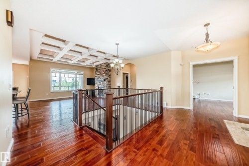 Rich wood-finish flooring throughout, complemented by a coffered ceiling and a stone-clad fireplace - 527 Callaghan Point(E), Edmonton, AB - Indoor Photo Showing Other Room