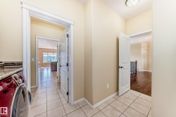 Tiled flooring extending into a laundry area with granite countertop and mosaic tile backsplash - 