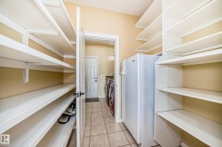 Utility room featuring extensive built-in shelving, tile flooring, and a white refrigerator - 
