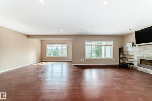 Spacious living area featuring wood-finish flooring, recessed lighting, and large windows - 527 Callaghan Point(E), Edmonton, AB - Indoor Photo Showing Other Room With Fireplace